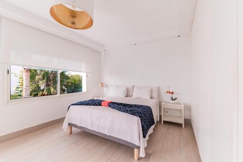 Una habitación blanca con una cama y una ventana en Villa Zen, piscine privée et plage, en Casablanca