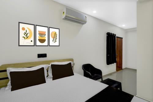 a bedroom with a white bed and a chair at Hotel O De' BVL Grand in Hyderabad