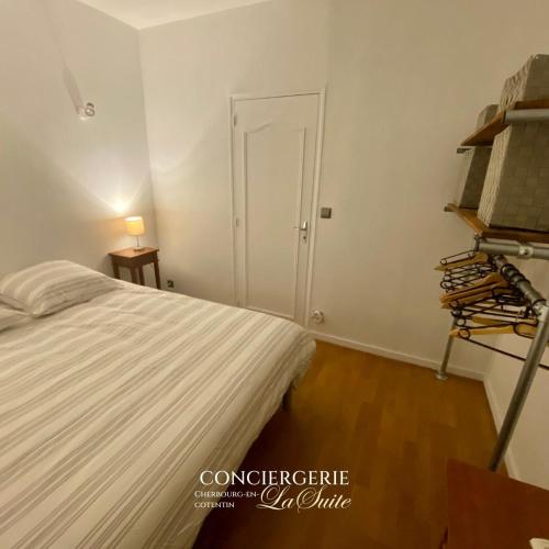 una camera da letto bianca con un letto e una porta di La Passerelle a Cherbourg en Cotentin