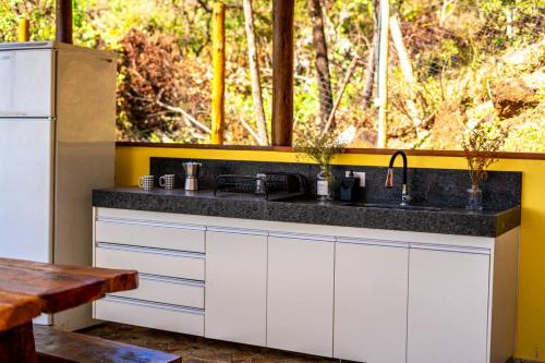 a kitchen with a counter with a sink and a window at Carcará Vacation Homes in Brumadinho