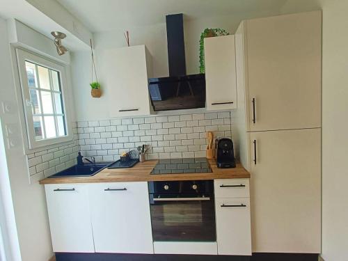 a kitchen with white cabinets and a stove top oven at Le Rez des Arcades - T2 en RDC hypercentre in Carentan