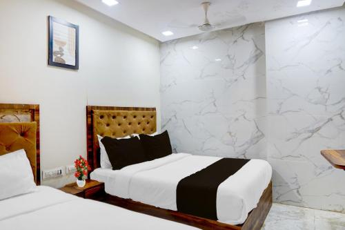 a bedroom with two beds and a marble wall at Hotel O Beverly Plaza Kurla in Mumbai