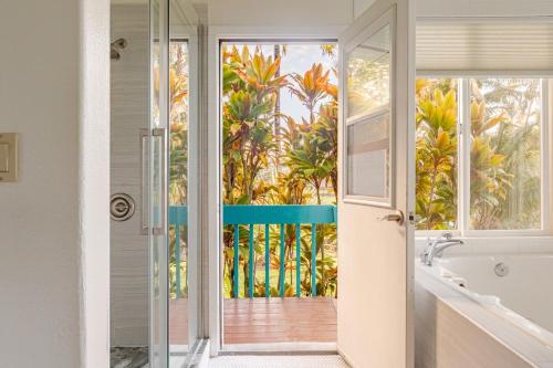 Grand Oceanfront Gated Estate on the Hamakua Coast في Hakalau: حمام مزود بحوض استحمام وباب زجاجي يؤدي إلى شرفة