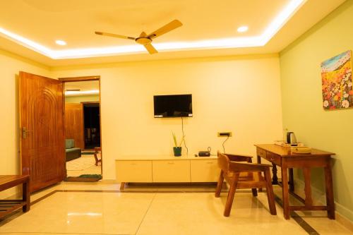 a living room with a table and a ceiling fan at Green Home Stay - 10 Mins Walk to Kanyakumari Main Beach in Kanyakumari