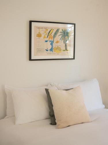 a picture hanging above a bed with white pillows at Le Boulevard par Maison Dudley in Lac-Mégantic