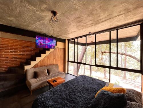a bedroom with a bed and a couch and a tv at Cabañas San Marcos in Mazamitla