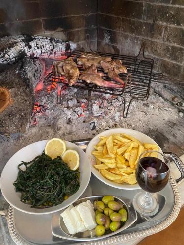 a table with three plates of food and a fire at Zeko Farm in Gjirokastër