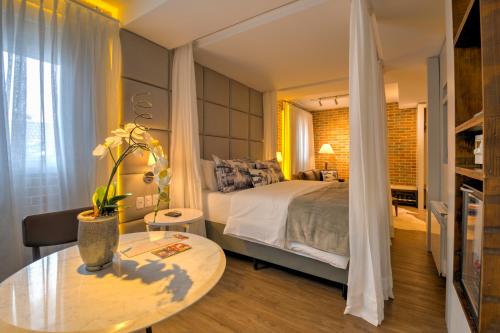 a bedroom with a large bed and a table with a table sidx sidx at Hotel Cercano in Gramado