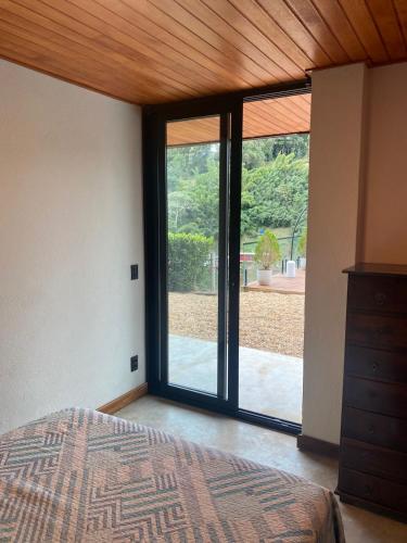 a bedroom with a bed and a large sliding glass door at Suíte Itaipava in Araras Petropolis