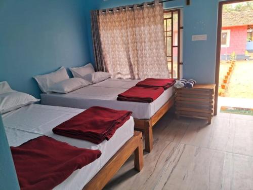 a bedroom with two beds with red sheets at Mantan Stay in Tadri