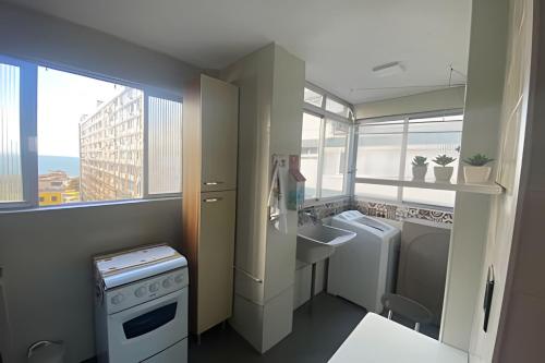a small bathroom with a sink and a washing machine at Lindo Sala Living com vista para o Mar in Santos