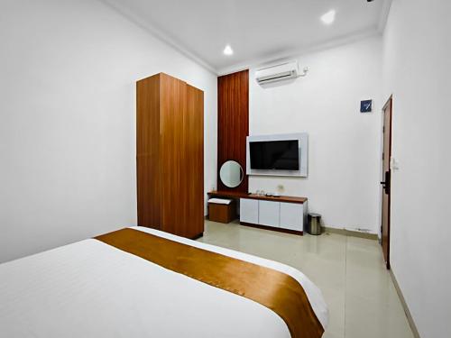a bedroom with a bed and a tv on the wall at Twins Hotel Boutique Syariah in Bandung