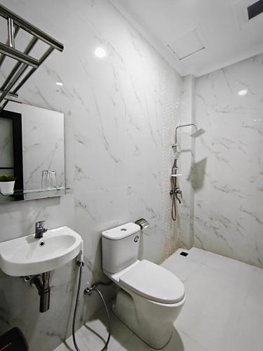 a white bathroom with a toilet and a sink at Twins Hotel Boutique Syariah in Bandung