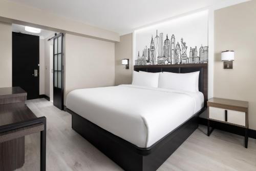 a bedroom with a large white bed with a city skyline at The Manhattan at Times Square Hotel in New York