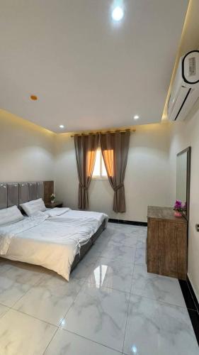 a bedroom with a large bed and a window at شقق يودج in Tabuk