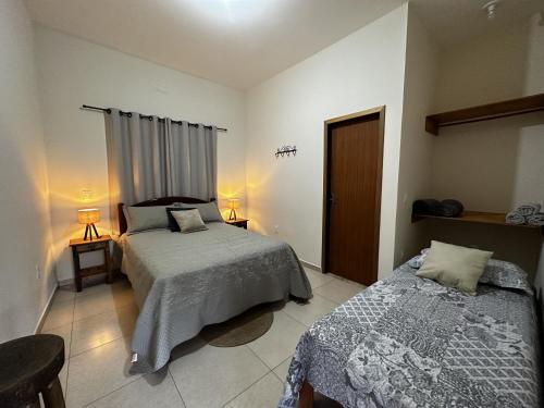 Un dormitorio con dos camas y una mesa y sillas. en Suíte Encanto do Paraíso - Cozinha - Self check-in, en Torrinha