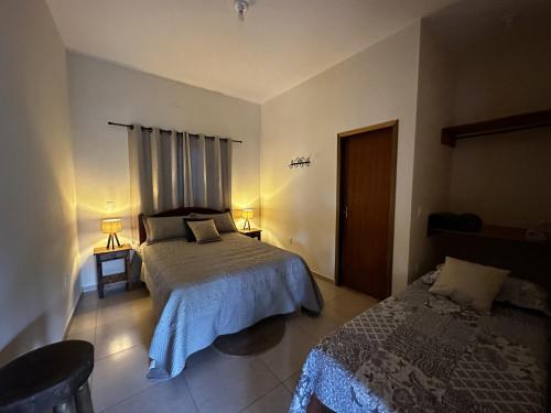 1 dormitorio con 2 camas, 2 mesas y 2 lámparas en Suíte Encanto do Paraíso - Cozinha - Self check-in, en Torrinha