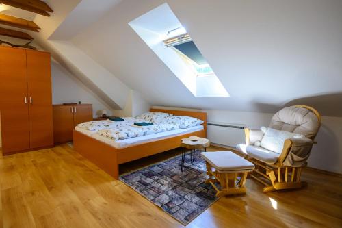 a attic bedroom with a bed and a chair at Apartmán Linda Tále in Tale