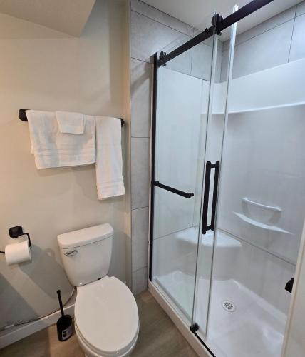 a bathroom with a toilet and a glass shower at Rhote's Luxury Suite in Saskatoon