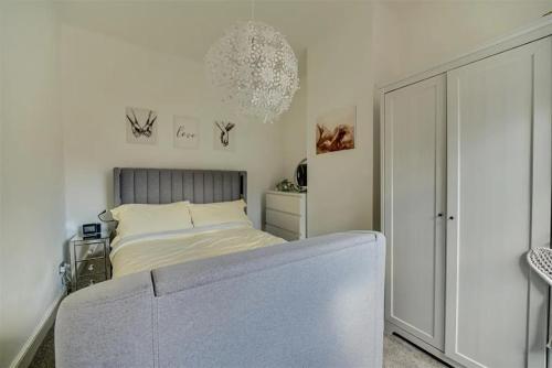 a white bedroom with a bed and a chandelier at Moody Street in Congleton