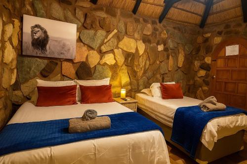 two beds in a room with a stone wall at Clarky's Pride Lodge in Alldays