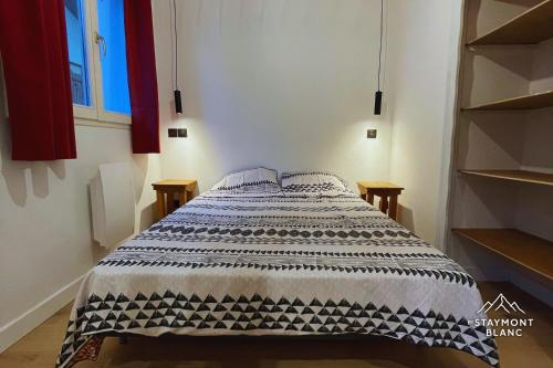 a bedroom with a bed with a black and white blanket at Charmant 2 pièces cosy au cœur de Saint-Gervais in Saint-Gervais-les-Bains
