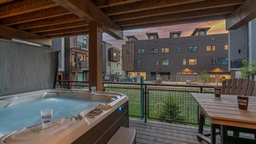 a hot tub on a deck with a table and a building at Princetown Grande in Steamboat Springs