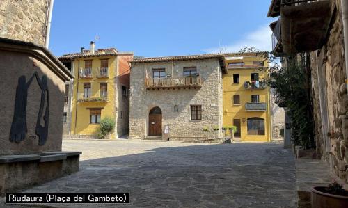 une rue vide dans une ville avec des bâtiments jaunes dans l'établissement Can d'Avall, à Riudaura