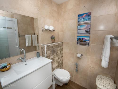 a bathroom with a white toilet and a sink at Siesta in Achziv in Nahariyya