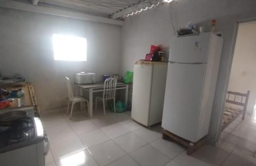 a kitchen with a refrigerator and a table with chairs at Casa de temporada in Caraguatatuba