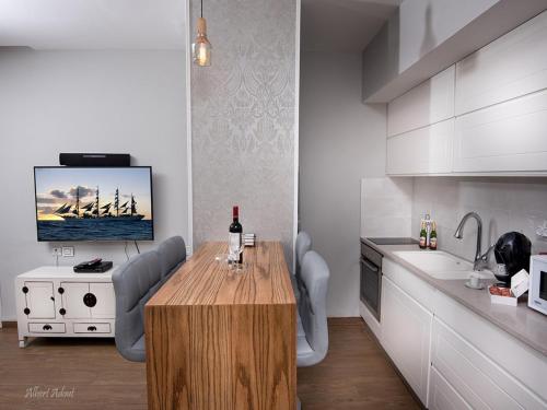 a kitchen with a wooden table with chairs and a tv at Siesta in Achziv in Nahariyya