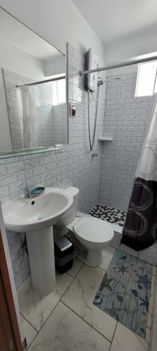 une salle de bain blanche avec un lavabo et des toilettes dans l'établissement Bravos Hospedaje Punta Negra, à Punta Negra