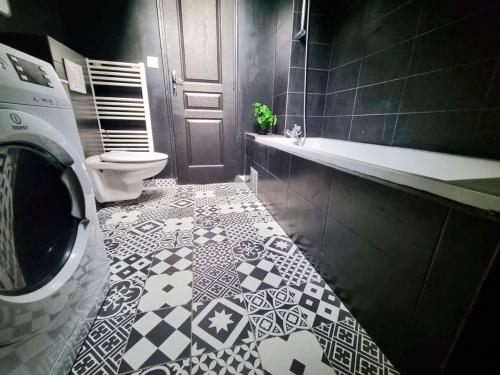 baño con aseo y suelo de baldosa blanco y negro. en L'appartement tranquillité, en Elbeuf