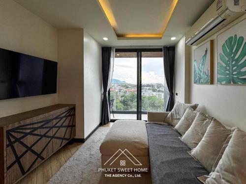 a living room with a couch and a flat screen tv at Condo sea view rawai beach by phuket sweet home in Rawai Beach