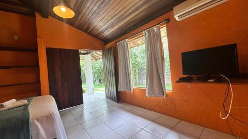 a living room with a television and a bedroom at Ibiza in Arraial d'Ajuda