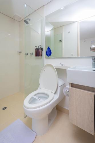 a white bathroom with a toilet and a shower at Hotel Laureles Plaza in Medellín