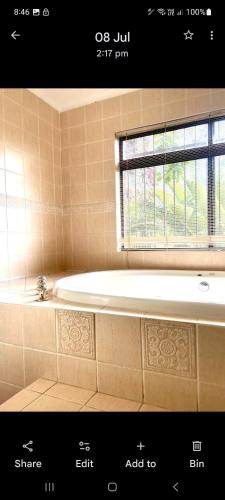 a bath tub in a bathroom with a window at Villa La Maison in Pretoria