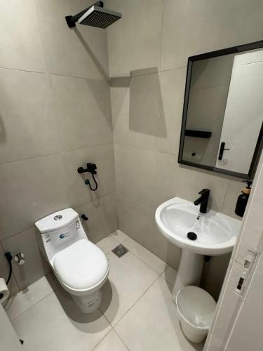 een witte badkamer met een toilet en een wastafel bij Smouha in Amman