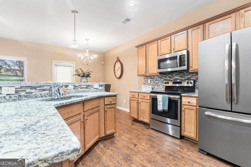 a kitchen with stainless steel appliances and wooden cabinets at Your Lawrenceville home in the heart of it all in Lawrenceville