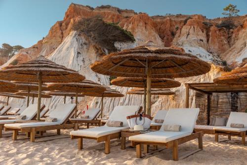 a group of chairs and umbrellas on a beach at EPIC SANA Algarve Hotel in Albufeira