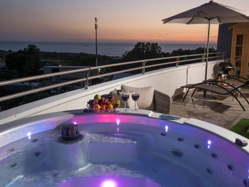 a hot tub on a balcony with a view of the ocean at Siesta in Achziv in Nahariyya