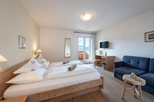 a bedroom with a large bed and a blue couch at Tirolerhof Guesthouse in Naz-Sciaves