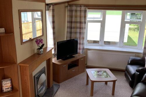 a living room with a tv and a couch and a fireplace at 2 Bed Caravan - Sleeps 6 - Pets - River Teviot in Hawick