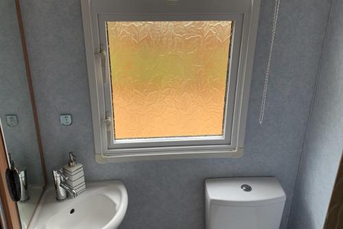 a bathroom with a window and a sink and a toilet at 2 Bed Caravan - Sleeps 6 - Pets - River Teviot in Hawick