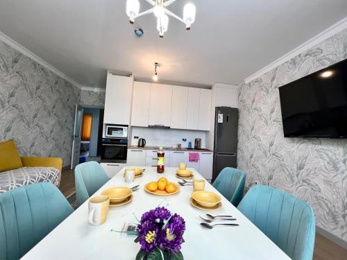 a dining room with a white table and blue chairs at Современный 3х комнатный апартаменты на Туране возле Барыс Арена in Astana