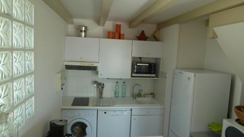 a small kitchen with a refrigerator and a sink at La Vague de Pontaillac 55m2 in Royan