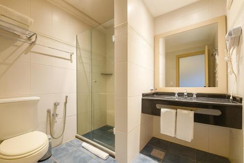 a bathroom with a toilet and a sink and a mirror at Suíte Confort - Resort no Coração de Gramado in Gramado