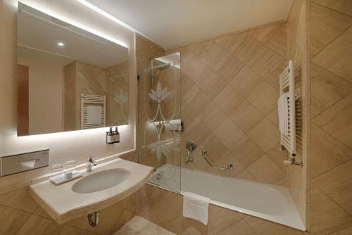 a bathroom with a sink and a tub and a mirror at NH Ravenna in Ravenna