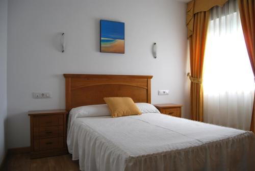a bedroom with a bed with a wooden headboard and a window at Hotel Plaza in Portonovo