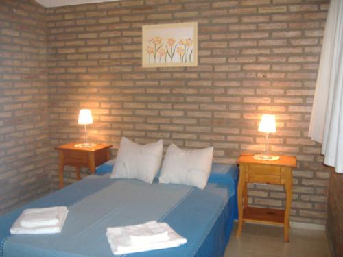 a bedroom with a blue bed and two night tables at Cabañas Acacias in San Antonio de Arredondo